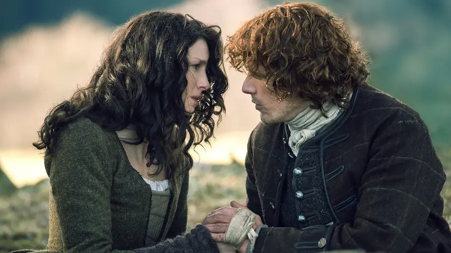 outlander „Outlander“: Claire und Jamie sitzen auf einer Wiese und küssen sich fast.