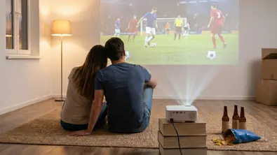 Paar in neuer Wohnung schaut Fußball per Beamer - Foto: TV Movie / KI Paar in neuer Wohnung schaut Fußball per Beamer - Foto: TV Movie / KI