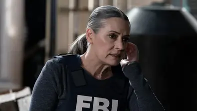 Paget Brewster mit FBI-Weste, sie fasst sich ans Ohr. - Foto: TMDB
