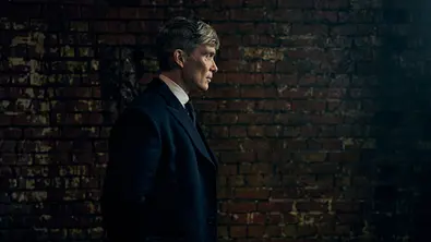 Tommy läuft vor einer Mauer aus Steinen. - Foto: Robert Viglasky / Netflix