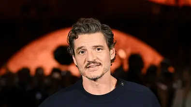 Pedro Pascal steht bei der Chanel Fashion Show vor dunklem Hintergrund und blickt in die Kamera. - Foto: IMAGO / Starface