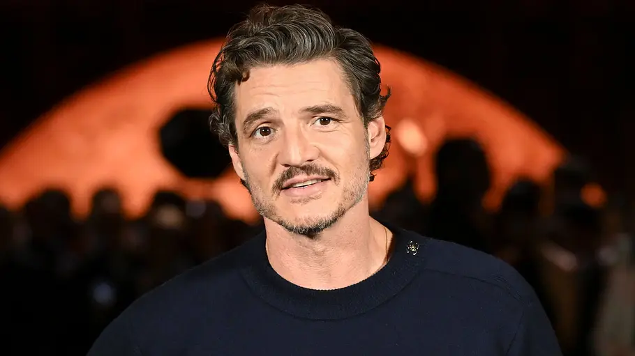 Pedro Pascal bei der Chanel Fashion Show Pedro Pascal steht bei der Chanel Fashion Show vor dunklem Hintergrund und blickt in die Kamera.