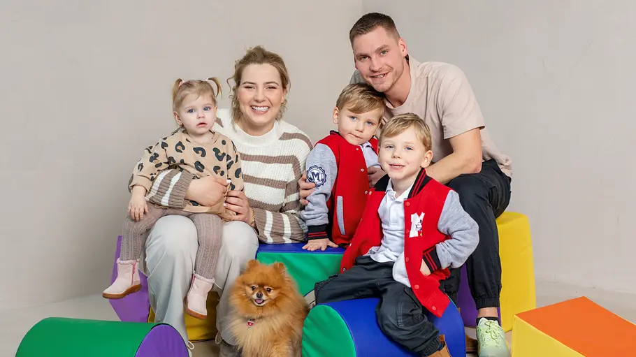 Peter und Sarafina Wollny samt Kinder Peter und Sarafina Wollny sitzen mit ihren Kindern auf und um bunten Elementen.
