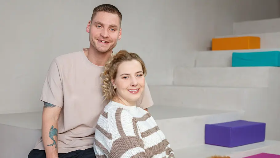Peter Wollny und Sarafina Wollny sitzen für ein Fotoshooting auf einer Treppe. Um sie herum stehen bunte Elemente.