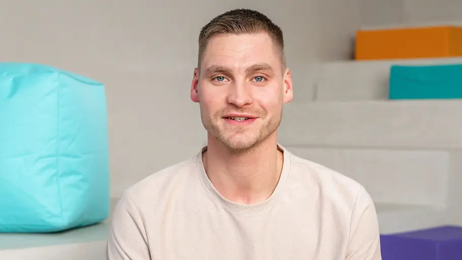 Peter Wollny Peter Wollny sitzt für ein Fotoshooting auf einer Treppe vor bunten Elementen.