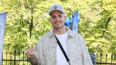 Pietro Lombardi trägt ein weißes Shirt, eine beige Jacke und eine graue Kappe. Er lächelt in die Kamera und zeigt mit der rechten Hand das „Peace-Zeichen - Foto: IMAGO / K.Piles