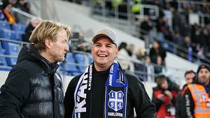 Pietro Lombardi bei einem Besuch im Fußballstadion lachend mit einem Karlsruhe-Schal um den Hals.  - Foto:  IMAGO / Jan Huebner