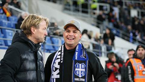 Pietro Lombardi bei einem Besuch im Fußballstadion lachend mit einem Karlsruhe-Schal um den Hals.  - Foto:  IMAGO / Jan Huebner