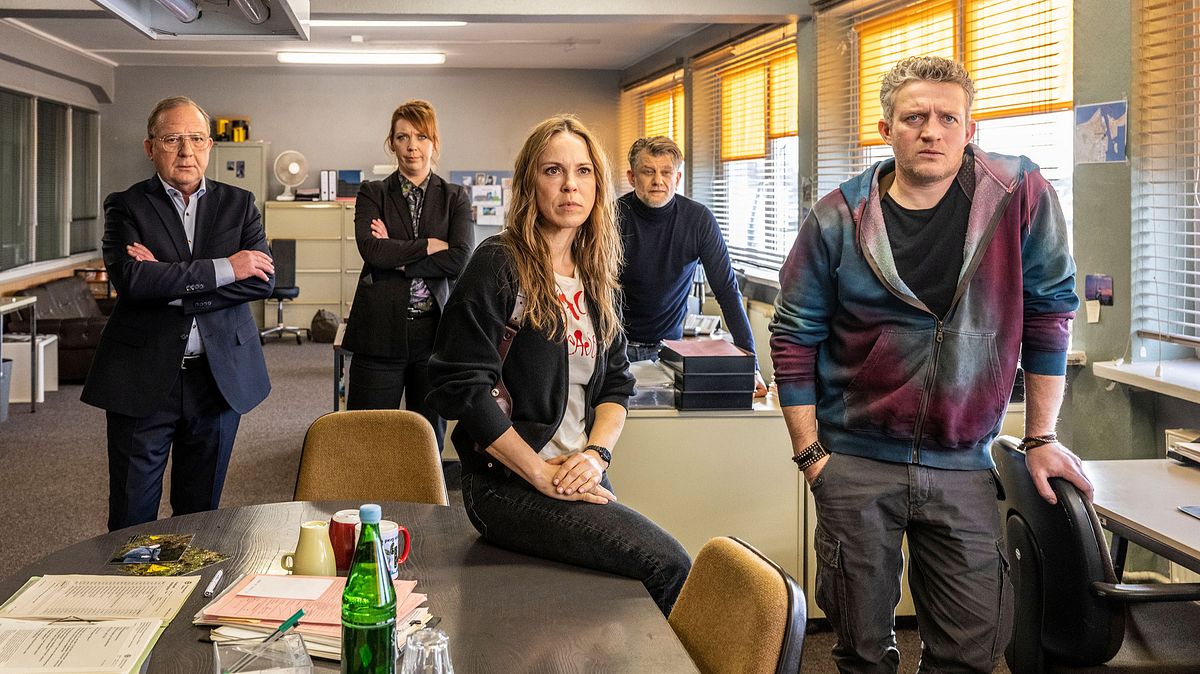 „Polizeiruf 110: Böse geboren“ läuft am 25. Mai. Henning Röder (Uwe Preuss), Melly (Lina Beckmann), Katrin König (Anneke Kim Sarnau) Anton Pöschel (Andreas Guenther) und Volker Thiesler (Josef Heynert) stehen und sitzen nebeneinander.
