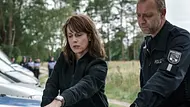 Claudia Michelsen steht als Ermittlerin Brasch neben einem weiteren Polizisten in der Natur. - Foto: MDR/filmpool fiction/Stefan Erhard Claudia Michelsen steht als Ermittlerin Brasch neben einem weiteren Polizisten in der Natur. - Foto: MDR/filmpool fiction/Stefan Erhard