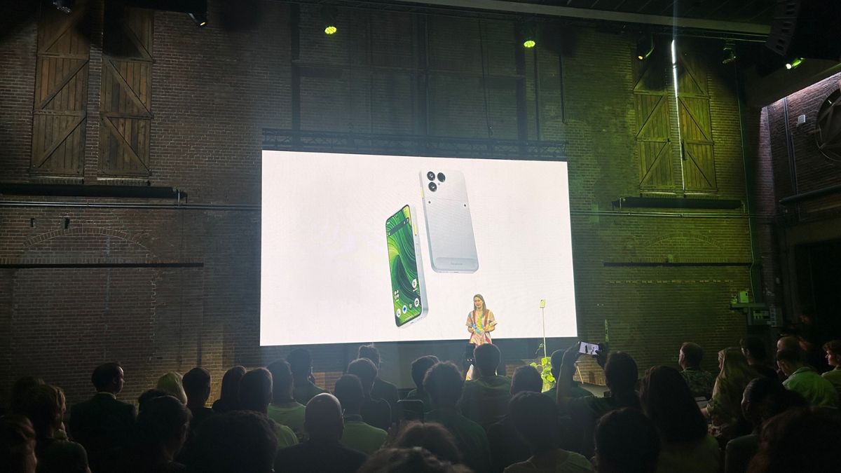 Präsentation Fairphone 6 Eine Frau steht vor einem Publikum und präsentiert, auf der Leinwand ist ein Smartphone zu sehen.