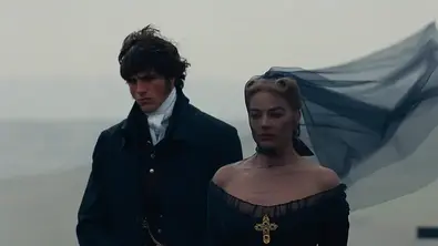 Jacob Elordi als Heathcliff und Margot Robbie als Cathy in „Wuthering Heights“ – Sturmhöhe: Ein Mann und eine Frau in dunkler, historischer Kleidung stehen an einem nebligen, windigen Ort. Der schwarze Schleier der Frau weht dramatisch im Wind, beide blicken ernst. - Foto: Warner Bros. Jacob Elordi als Heathcliff und Margot Robbie als Cathy in „Wuthering Heights“ – Sturmhöhe: Ein Mann und eine Frau in dunkler, historischer Kleidung stehen an einem nebligen, windigen Ort. Der schwarze Schleier der Frau weht dramatisch im Wind, beide blicken ernst. - Foto: Warner Bros.