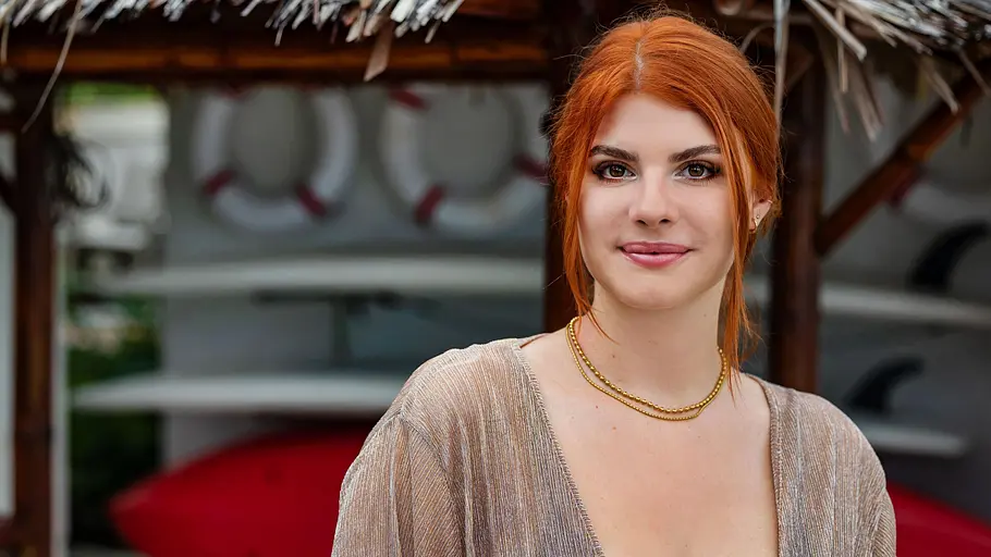 Princess Charming Kandidatin Kelly: Mit Orange gefärbten Haaren, einem dunklen Augenmakeup und einem leichtes Lächeln schaut sie in die Kamera.