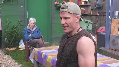 Gedeon Burkhard und Christian Lell sind vor einer grünen Gartenhütte zu sehen, einer sitzt, der andere trägt Kappe und Weste. - Foto: Joyn Gedeon Burkhard und Christian Lell sind vor einer grünen Gartenhütte zu sehen, einer sitzt, der andere trägt Kappe und Weste. - Foto: Joyn