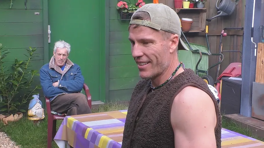 Gedeon Burkhard und Christian Lell Gedeon Burkhard und Christian Lell sind vor einer grünen Gartenhütte zu sehen, einer sitzt, der andere trägt Kappe und Weste.