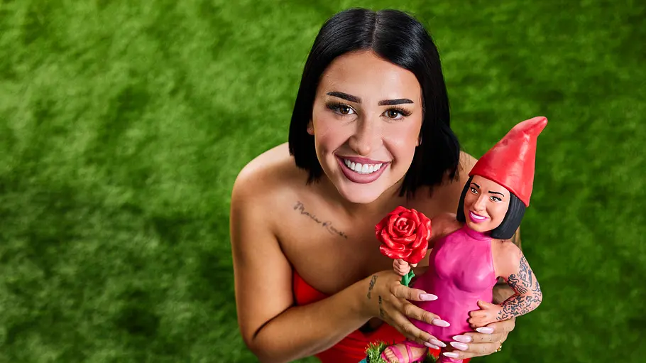 Francesca Morgese Francesca Morgese lächelt auf grünem Rasen in die Kamera und hält eine pink gekleidete Zwergenfigur mit roter Mütze und Rose.