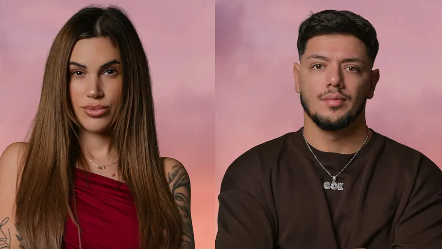 Rebecca und Gök Rebecca und Gök im Porträt vor rosa Hintergrund, beide stehen mit verschränkten Armen und blicken ernst in die Kamera