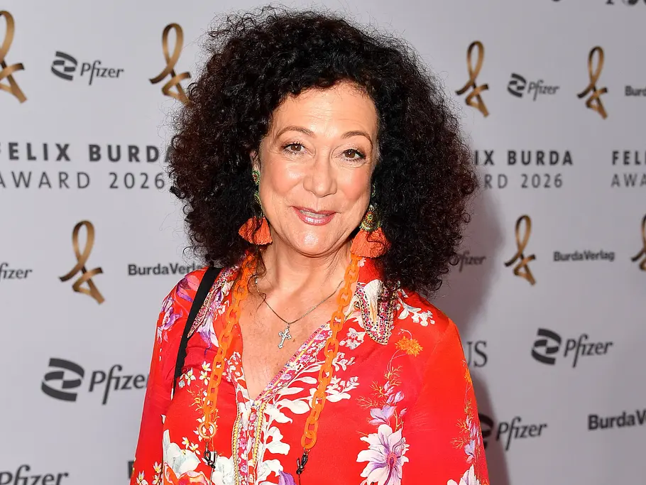 Quiz-Champion: Österreich-Deutschland-Special mit Barbara Wussow Barbara Wussow lächelt in einer rot geblümten Bluse mit orangefarbenen Ohrringen vor einer Logowand des Felix Burda Award 2026.