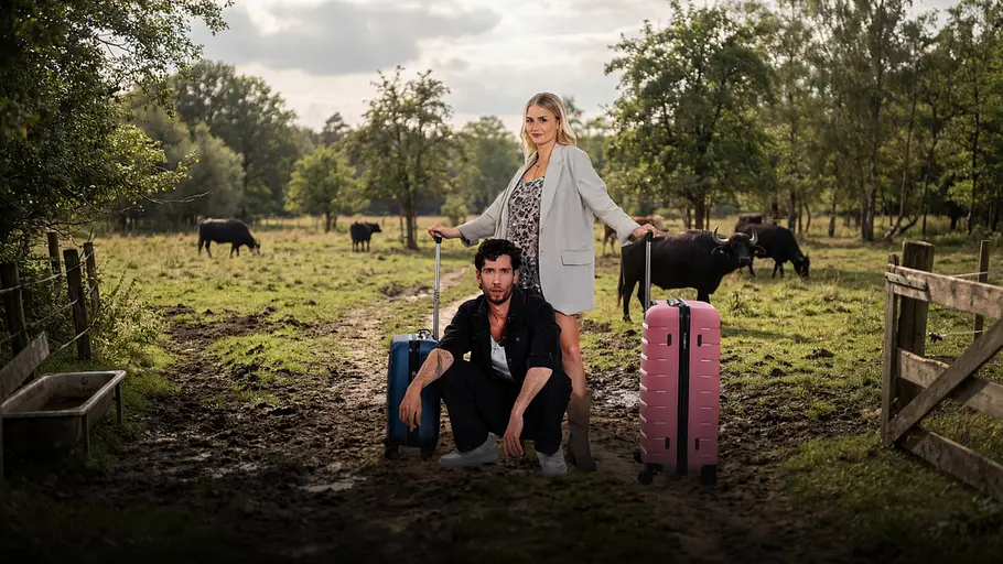 Rapper Ferry (30) und Yoga-Lehrerin Kathy (29) mit Koffern vor einer Kuhweide.