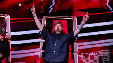 Juror Rea Garvey streckt die Hände nach oben und jubelt auf seinem Sitz bei The Voice of Germany - Foto: Joyn / ProSieben