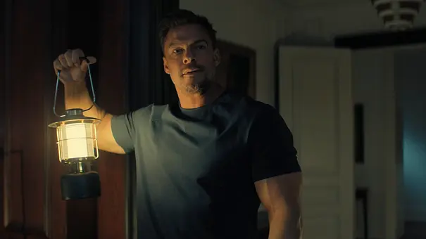 Alan Ritchson leuchtet mit einer Laterne ein dunkles Haus aus. - Foto: © Amazon Content Services LLC Alan Ritchson leuchtet mit einer Laterne ein dunkles Haus aus. - Foto: © Amazon Content Services LLC