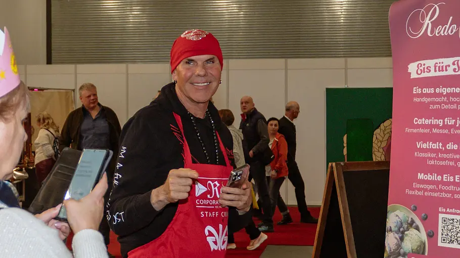 Gastronom Rene Dost präsentiert sein Angebot am Stand von Redo Gelato mit rotem Bandana und roter Schürze. 
