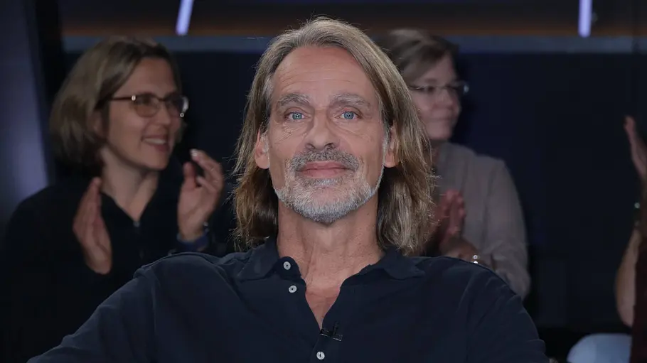 Richard David Precht Richard David Precht sitzt mit überschlagenen Beinen im Sessel. Hinter ihm klatschen Zuschauerinnen.