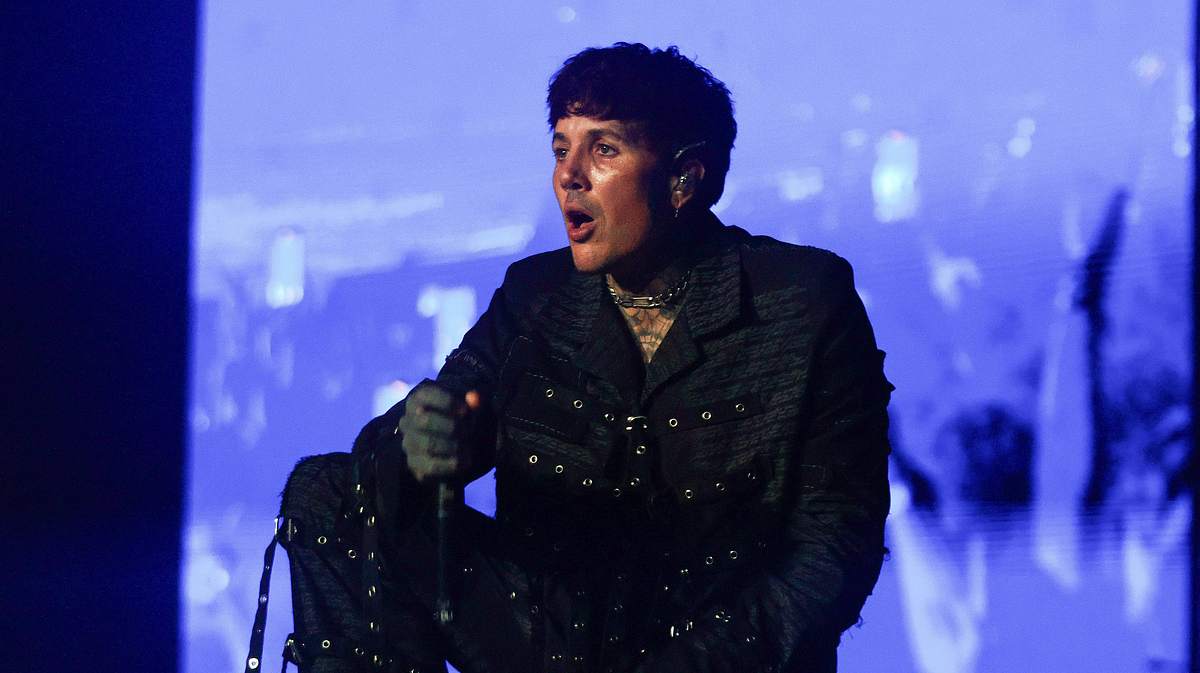 Bring Me The Horizon Oliver Sykes kniend auf der Bühne mit einem Mikrofon in der Hand
