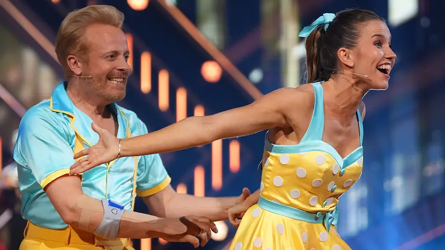 Ross Antony lacht, Mariia Maskina schlägt die Arme nach hinten.