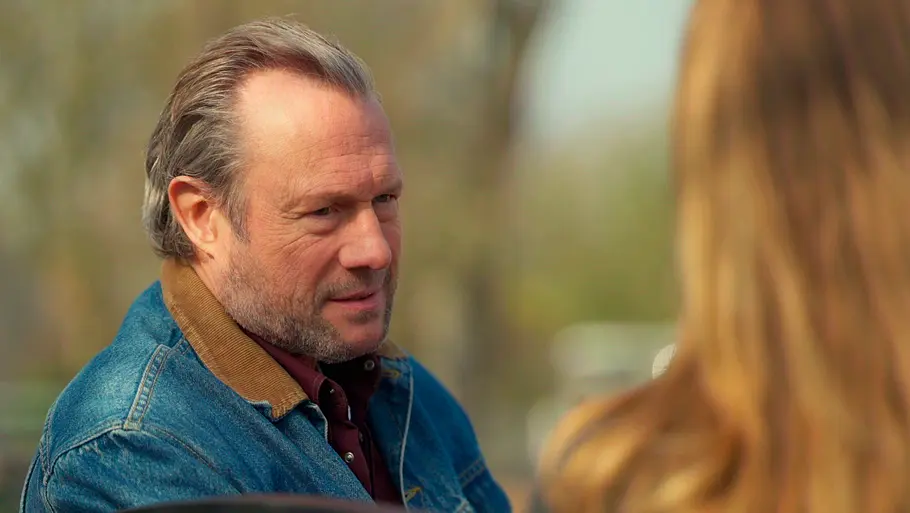 „Rote Rosen“ Folge 4391, 5. Oktober 2026 Rote Rosen-Vorschau Folge 4391: Michael trägt eine Jeansjacke und blickt Carla an, die im Vordergrund unscharf von hinten zu sehen ist.