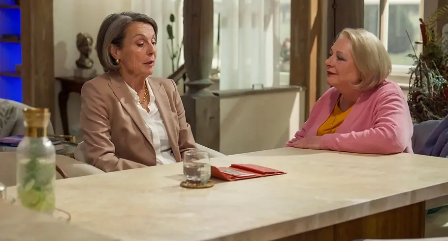 Rote Rosen Victoria und Gisela Victoria und Gisela sitzen an einem hellen Tisch, eine im beigen Blazer, die andere in einer rosa Strickjacke.