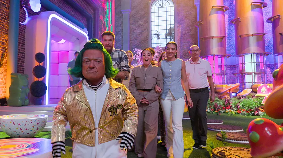 Rusty Goffe führt eine neue Generation durch Wonkas Fabrik Rusty Goffe läuft als Oompa Loompa durch Wonkas Schokoladenfabrik und führt die Kandidat:innen hinter sich her.