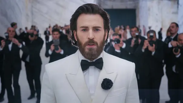 Mike Tyler (Chris Evans) trägt einen weißen Smoking mit schwarzer Fliege und Ansteckblume. Hinter ihm stehen Fotografen. - Foto: © ICONOCLAST, Mid March Media, Film4, Heretic Mike Tyler (Chris Evans) trägt einen weißen Smoking mit schwarzer Fliege und Ansteckblume. Hinter ihm stehen Fotografen. - Foto: © ICONOCLAST, Mid March Media, Film4, Heretic