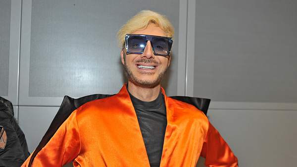 Sam Dylan lächelt in einem orangen Outfit und Sonnenbrille in die Kamera. - Foto: IMAGO / STAR-MEDIA