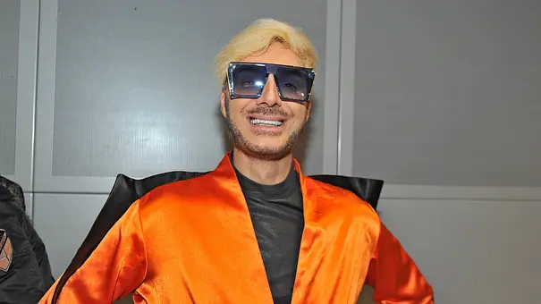 Sam Dylan lächelt in einem orangen Outfit und Sonnenbrille in die Kamera. - Foto: IMAGO / STAR-MEDIA
