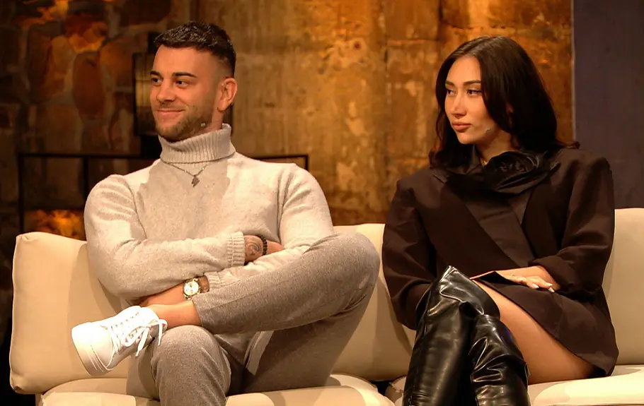 Serkan und Samira sitzen auf der Couch und schauen ernst.