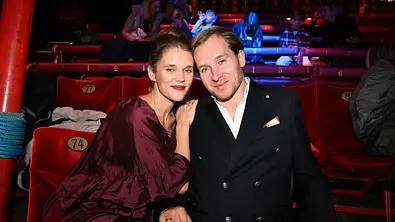 Sarah Elena und Samuel Koch sitzen lächelnd nebeneinander. Sie legt ihm die Hand auf die Schulter. - Foto: IMAGO / Lindenthaler