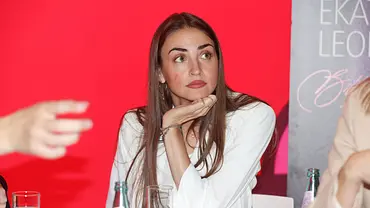 Ekaterina Leonova sitzt in weißer Bluse vor rotem Hintergrund an einem Tisch und stützt das Kinn auf ihre Hand. - Foto: IMAGO / Future Image