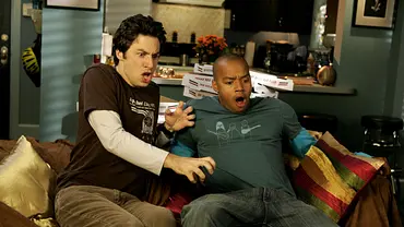 Zwei junge Männer sitzen auf einem Sofa in einer Wohnung und reagieren erschrocken auf etwas vor ihnen; im Hintergrund sind eine offene Küche und mehrere Pizzakartons zu sehen. - Foto: epp/ TOUCHSTONE PICTURES