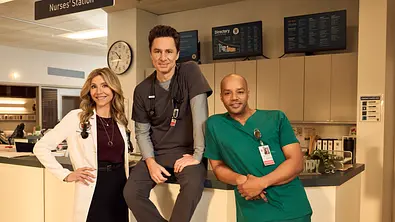 Elliot, J.D. und Turk stehen vor, sitzen auf und lehnen am Empfang eines Krankenhauses. - Foto: © 2025 Disney. All rights reserved. Elliot, J.D. und Turk stehen vor, sitzen auf und lehnen am Empfang eines Krankenhauses. - Foto: © 2025 Disney. All rights reserved.