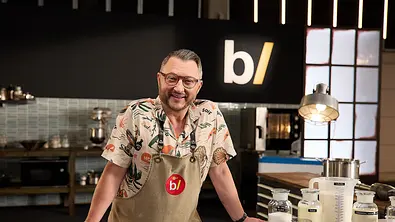Sebastian Lege steht lächelnd mit Brille, buntem Hemd und Schürze hinter einer Küchentheke mit Zutaten in Glasgefäßen. - Foto: ZDF/Kai Schulz Sebastian Lege steht lächelnd mit Brille, buntem Hemd und Schürze hinter einer Küchentheke mit Zutaten in Glasgefäßen. - Foto: ZDF/Kai Schulz