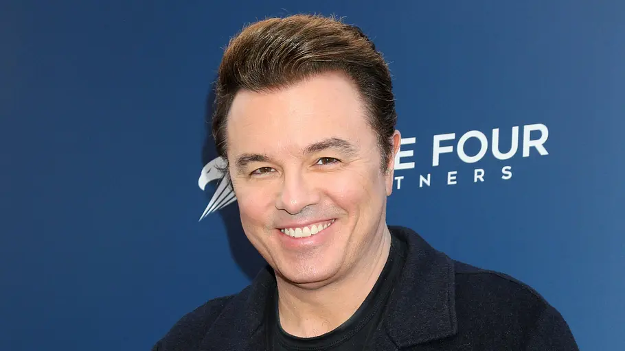 Seth MacFarlane Seth MacFarlane lächelt freudig vor einer blauen Fotowand.