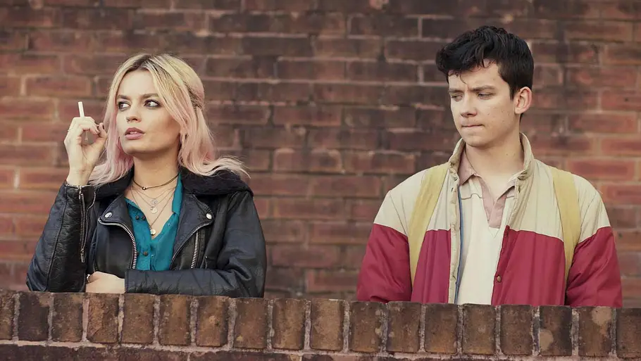 Maeve und Otis stehen in „Sex Education“ vor einer Schulmauer.
