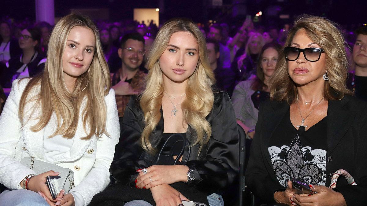 Shania und Davina Geiss. Man sieht Shania, Davina und Carmen Geiss, die „glamourös anmutend auf einer öffentlichen Veranstaltung sitzen.