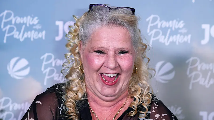 Silvia Wollny Silvia Wollny lacht voller Freude vor einer Fotowand von „Promis unter Palmen“.