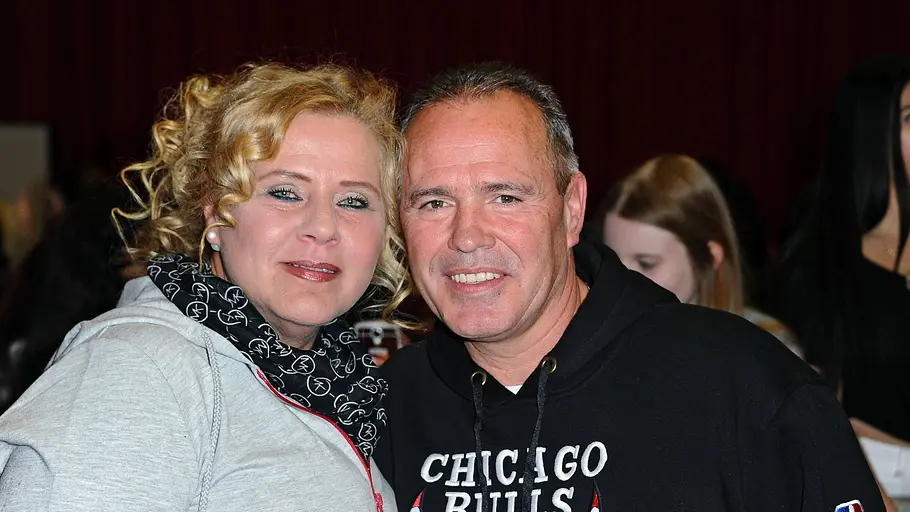 Silvia Wollny und Harald Elsenbast lächeln in die Kamera. Sie trägt ein schwarzes Tuch und eine graue Strickjacke und er einen schwarzen Pullover mit der Aufschrift „Chicago Bulls