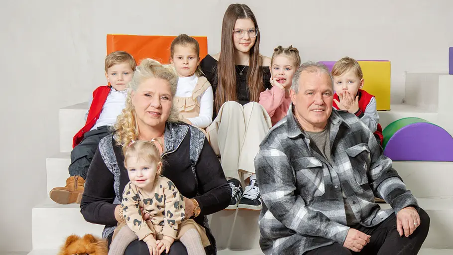 Silvia Wollny sitzt mit Harald und ihren Enkelkindern auf einer Treppe vor bunten Elementen. 