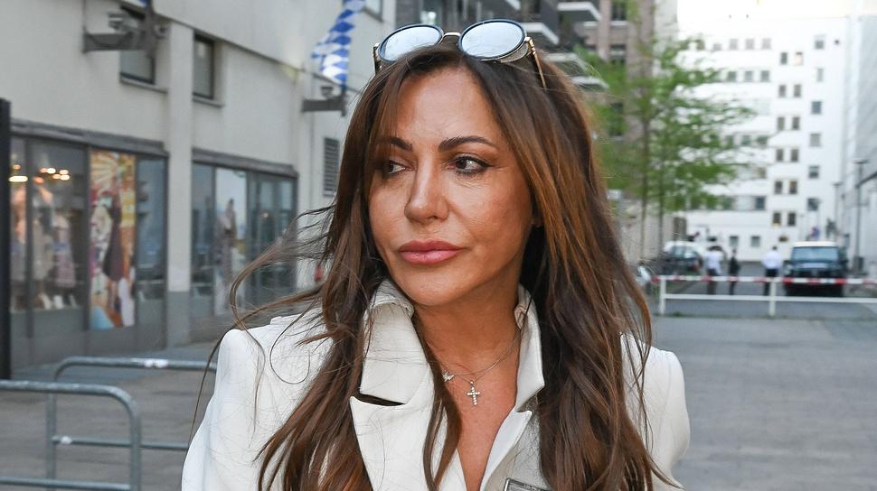 Simone Thomalla mit ernstem Blick zur Seite, Sonnenbrille auf dem Kopf und in einem weißen Lederanzug. - Foto:  IMAGO / pictureteam