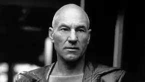 Sir Patrick Stewart als Jean-Luc Picard trägt eine dunkle Jacke und blickt ernst nach vorn. Die Aufnahme ist schwarz-weiß. - Foto: TMDB Sir Patrick Stewart als Jean-Luc Picard trägt eine dunkle Jacke und blickt ernst nach vorn. Die Aufnahme ist schwarz-weiß. - Foto: TMDB