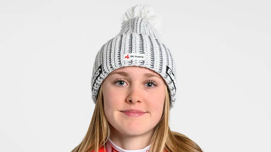 Katharina Engelhardt Porträt der österreichischen Skirennläuferin Katharina Engelhardt in dunkelblauer Teamjacke und grauer Strickmütze mit Bommel vor hellem Hintergrund. Sie blickt direkt in die Kamera und trägt die Ausrüstung des österreichischen Skiverbands mit Sponsorlogos.